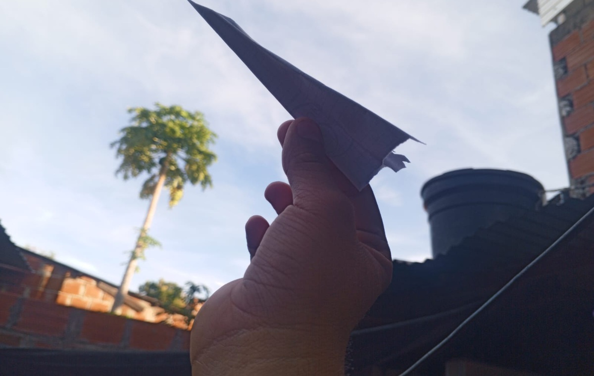 Avión de papel sostenido con la mano frente al cielo.